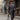 Man in a gray suit and hat walking down a street holding an umbrella.