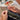 Close-up of hands sewing a green fabric with a blurred indoor background
